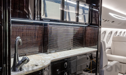 Galley in dark wood tones with granite-look counter in Falcon 7X by Duncan Aviation