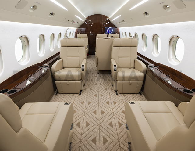 Newly refurbished interior of Falcon 2000 by Duncan Aviation showing 10 leather seats, tan geometric carpet and dark wood accents