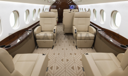 Newly refurbished interior of Falcon 2000 by Duncan Aviation showing 10 leather seats, tan geometric carpet and dark wood accents