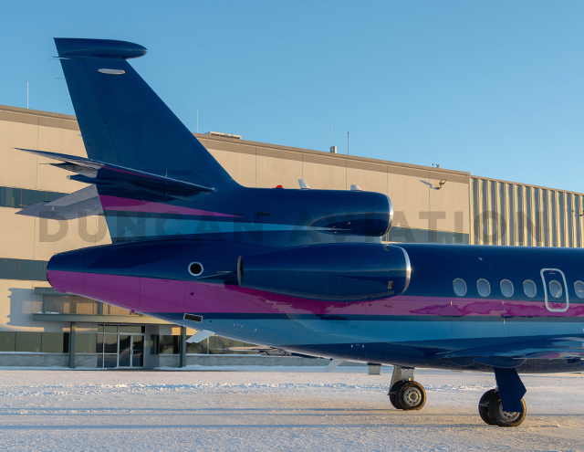 Tail of newly painted Falcon 900 with matching magenta and navy stripe against dark blue background