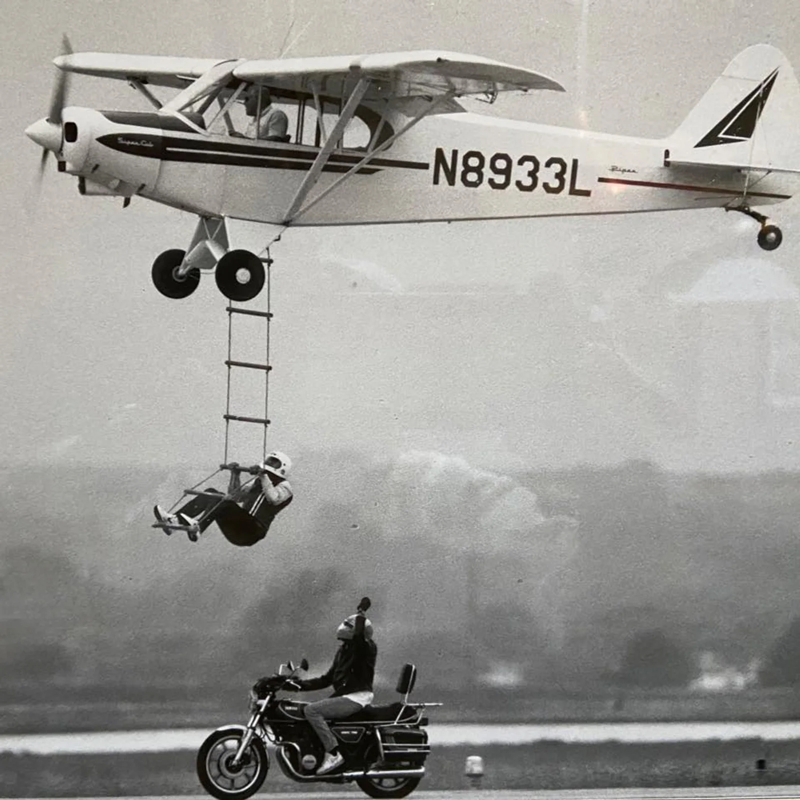 An employee party airshow favorite: Harry Barr flies as Don Fielder climbs the rope ladder from a motorcycle driven by Ed Bowes.